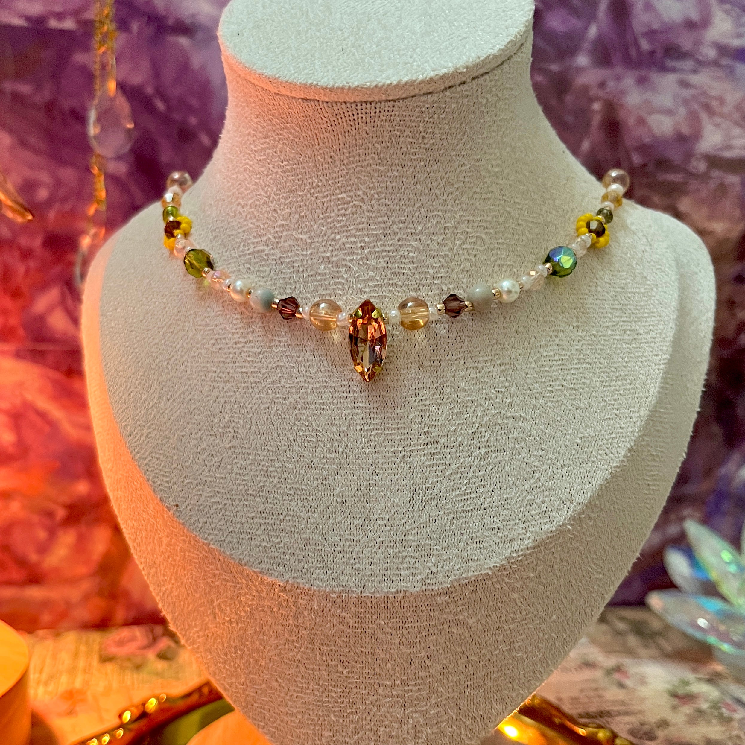 Necklace with multicolored beads on a mannequin bust against a decorative background